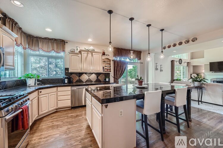 A kitchen with a black countertop and wooden floors.