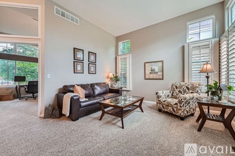 A living room with a black leather couch and a patterned armchair.