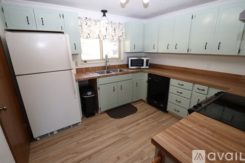 A kitchen with a white refrigerator, wooden cabinets, and a wooden countertop.