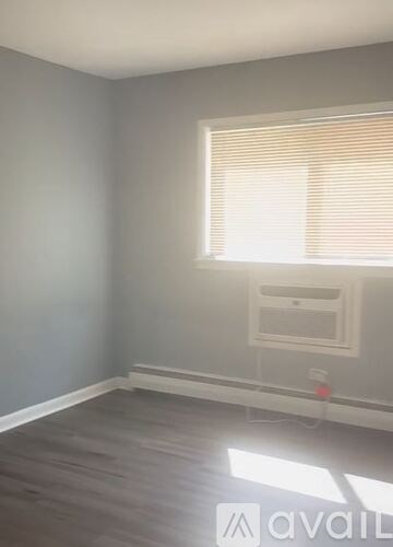A room with a window and blinds, and a wall-mounted shelf.