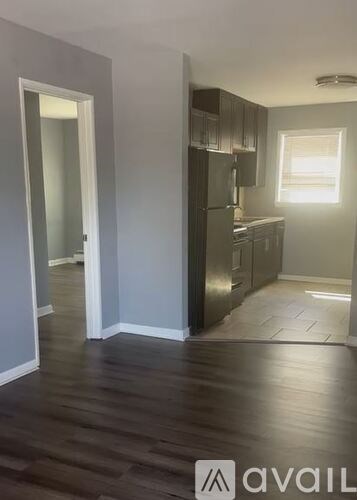 A kitchen with dark wood floors and white walls.
