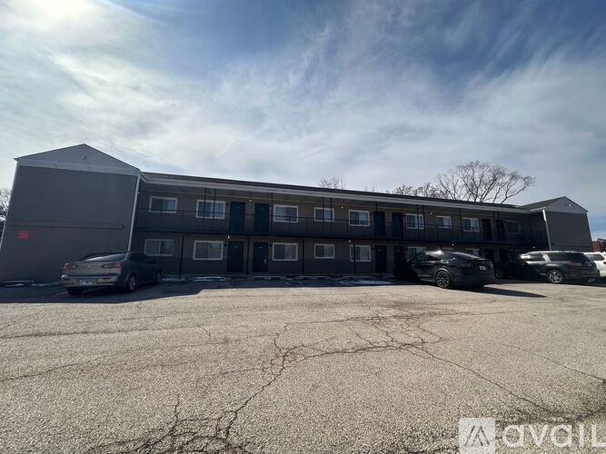 A grey building with a parking lot in front of it.