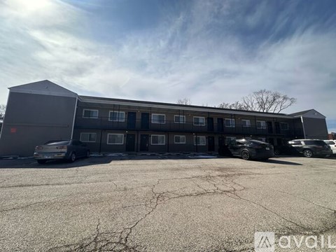 A grey building with a parking lot in front of it.