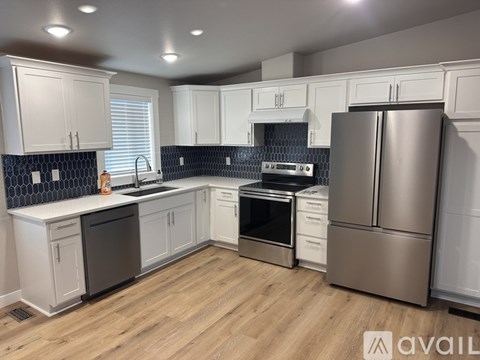 A kitchen with white cabinets and a stainless steel refrigerator.