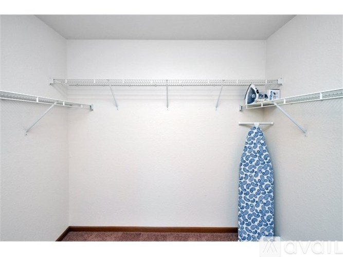 A room with a white wall and a blue and white patterned tie hanging on a clothes rack.