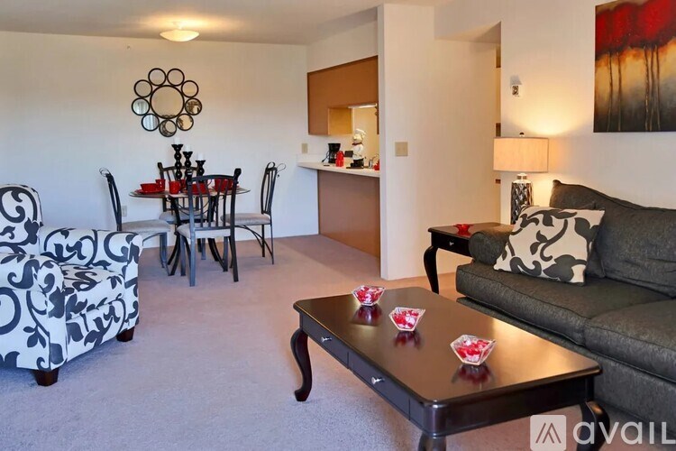 A living room with a grey couch, a coffee table with red coasters, and a dining table with chairs.