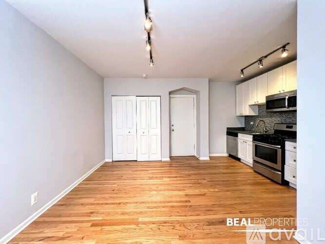 A spacious kitchen with wooden floors and white walls.