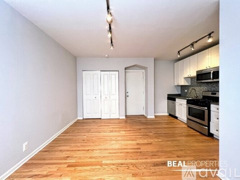 A spacious kitchen with wooden floors and white walls.