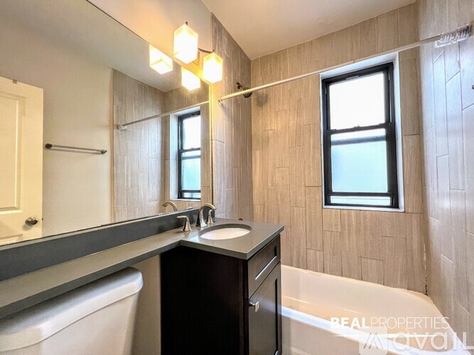 A bathroom with a tub, sink, mirror, and lighting fixtures.