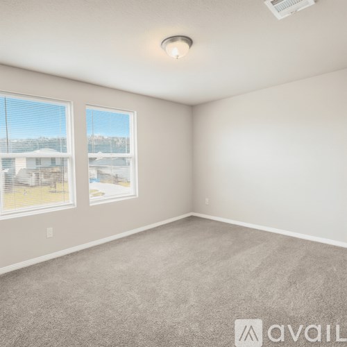 A room with a carpeted floor and two windows.