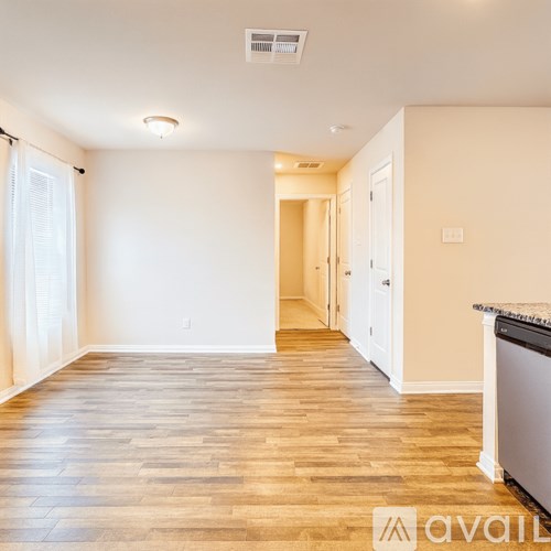 A spacious room with wooden flooring and white walls.