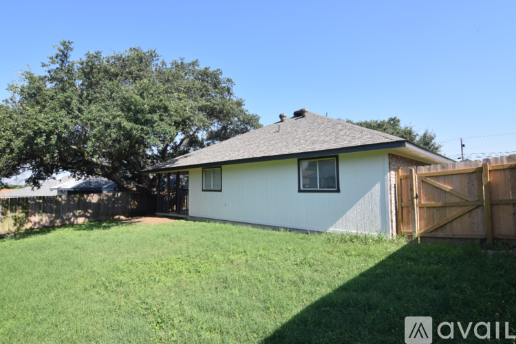 A house with a white exterior and a brown roof is surrounded by a green lawn.