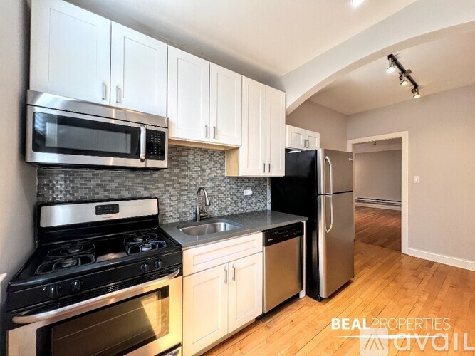 A kitchen with a stove, oven, microwave, refrigerator, and sink.