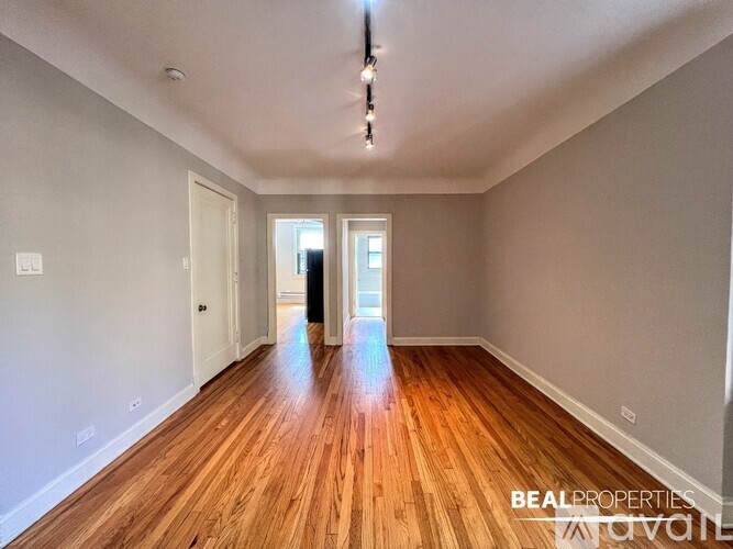 A spacious room with wooden floors and white walls.