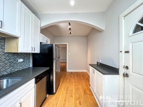 A kitchen with white cabinets and a black refrigerator.