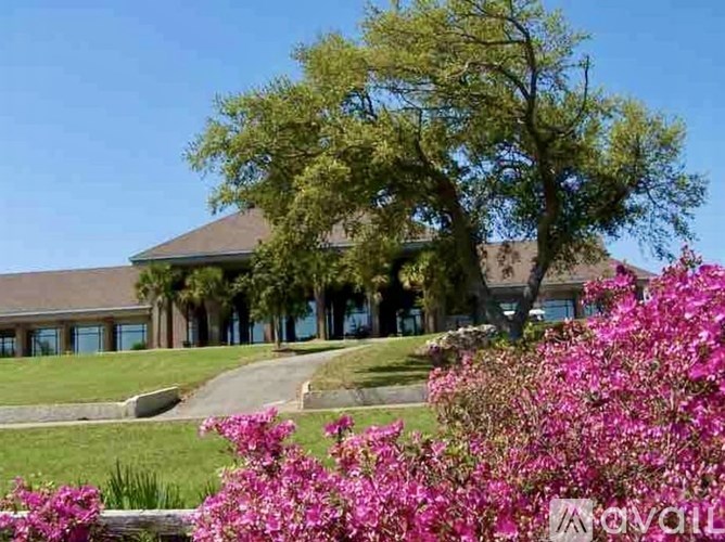 A house with a tree and pink flowers in front.