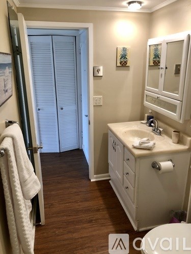 A white bathroom with a sink and a towel hanging on the door.