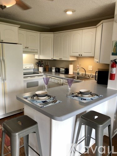 A kitchen with white cabinets and a white refrigerator.