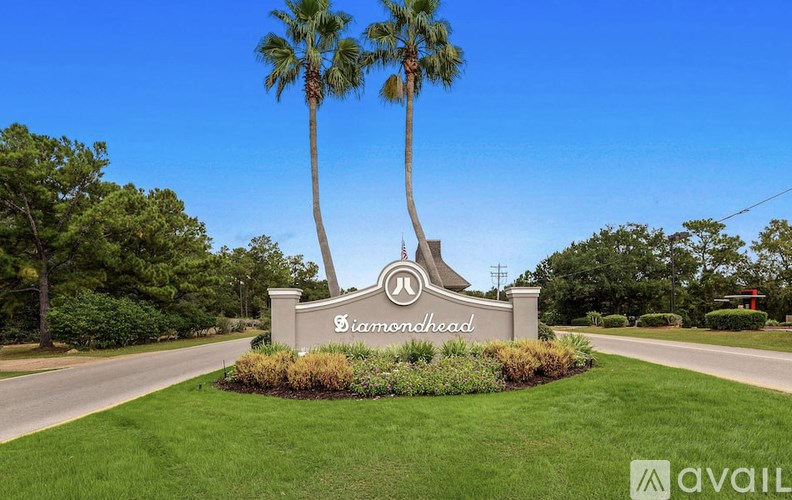 A sign for a community named "Ramhead" is displayed in front of a well-manicured lawn with palm trees.