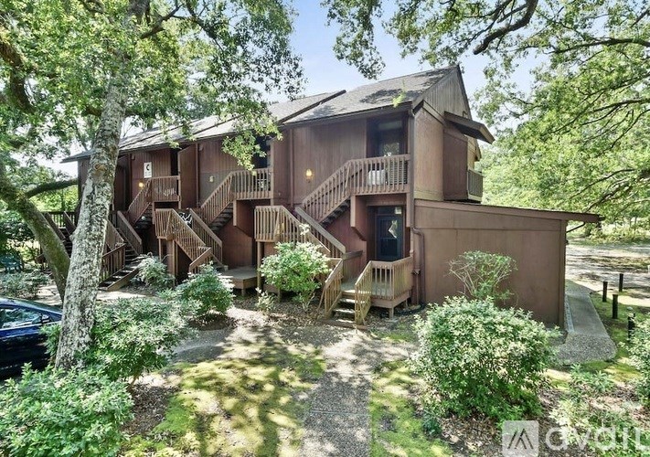 A house with a balcony and a staircase surrounded by greenery.