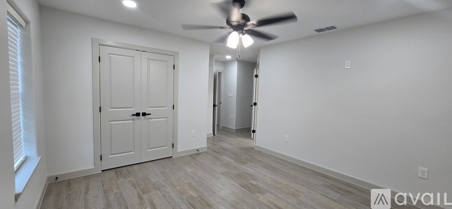 A room with a white door and a ceiling fan.