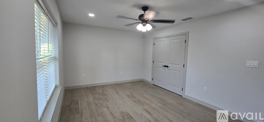 A room with a ceiling fan and a door.