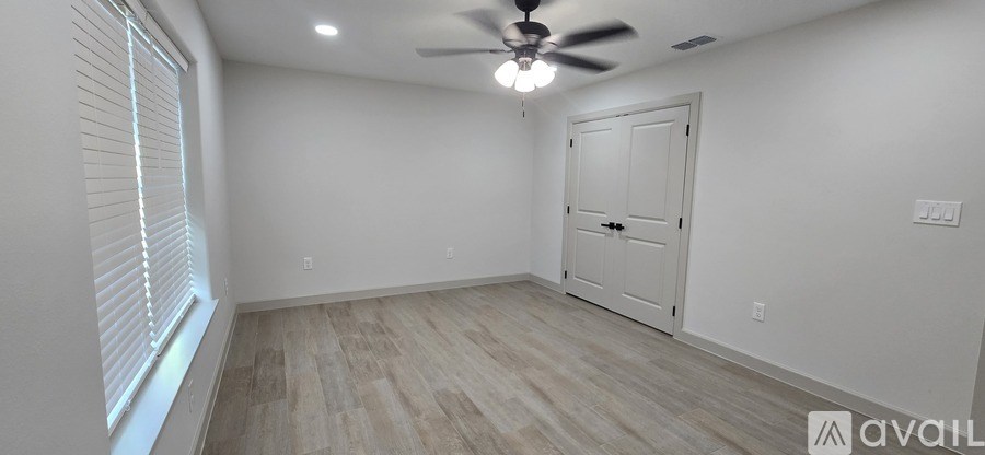 A room with a ceiling fan and a door.