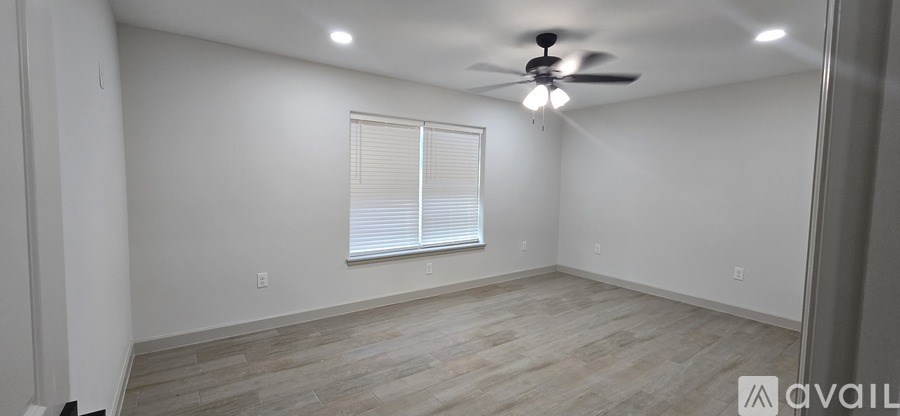 A room with a ceiling fan and a window with blinds.