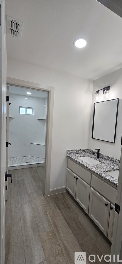 A bathroom with a sink, mirror, and a walk-in shower.