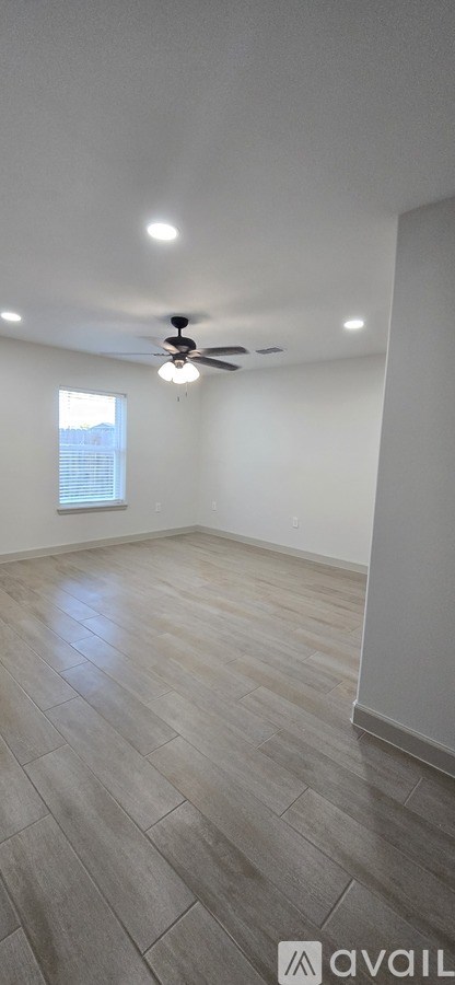 A room with a ceiling fan and wooden flooring.