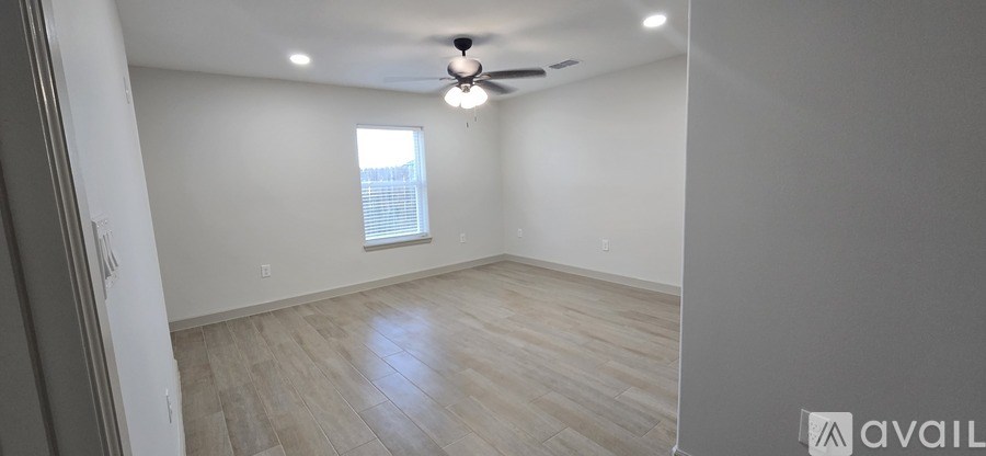 A spacious room with a window and a ceiling fan.