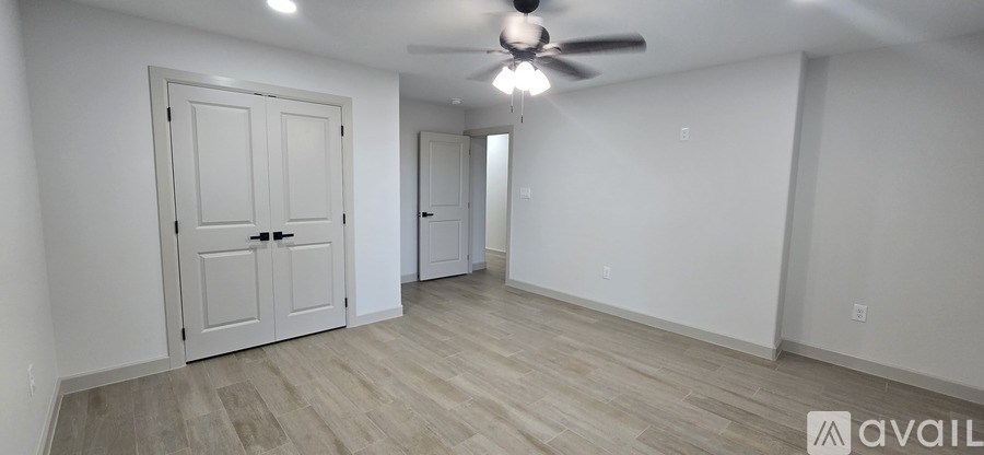 A room with a ceiling fan and two doors.