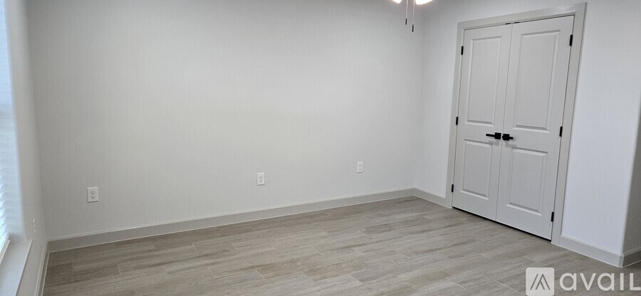 A room with a white door and wooden flooring.