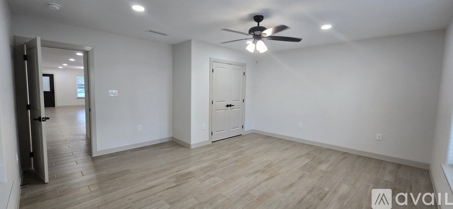 A spacious room with a ceiling fan and lighting fixture.