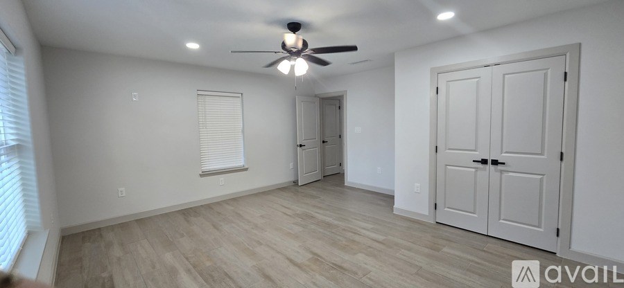 A spacious room with a ceiling fan and a door on the right.