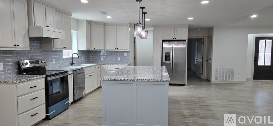 A kitchen with white cabinets and a marble countertop.