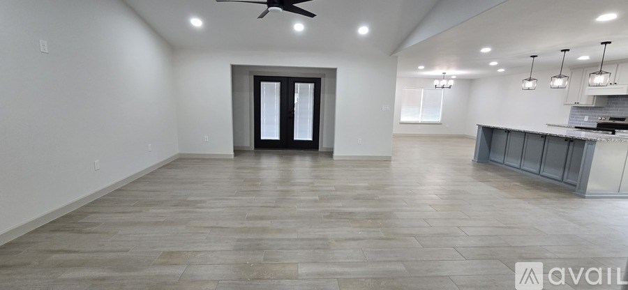A spacious room with a ceiling fan and a bar area.