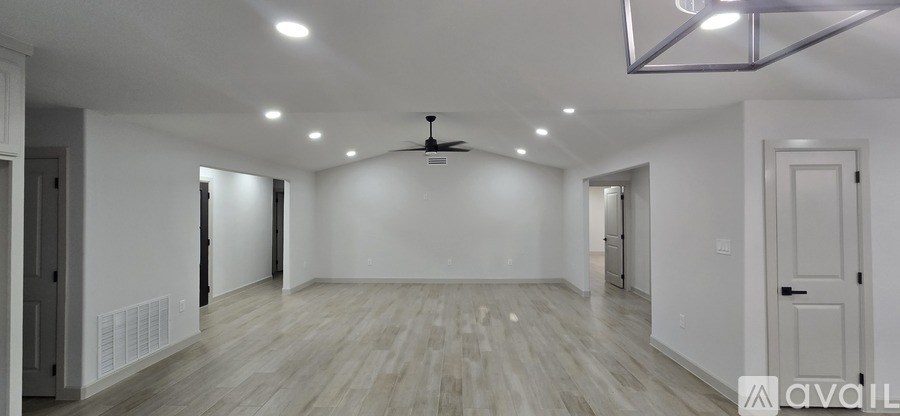 A spacious room with wooden flooring and a ceiling fan.