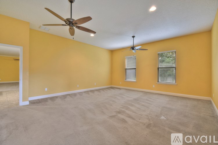A room with a ceiling fan and carpeted floor.