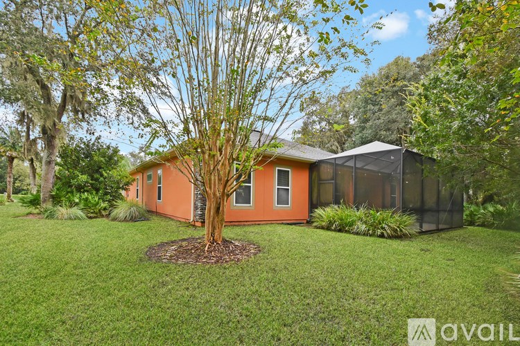 A tree in a mulched circle is in front of a house with a screened in area.