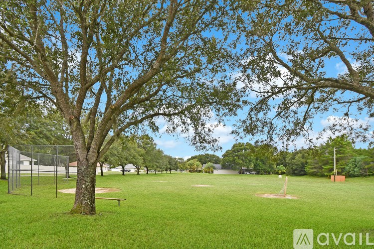 A baseball field with a tree in the foreground and a fence in the background.