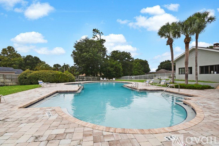 A swimming pool surrounded by a brick patio and palm trees.