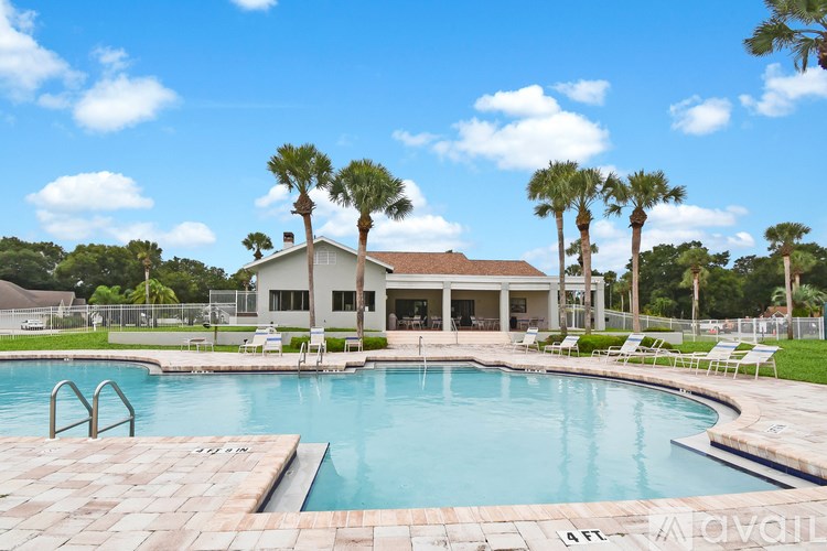 A pool with a building behind it and palm trees around.