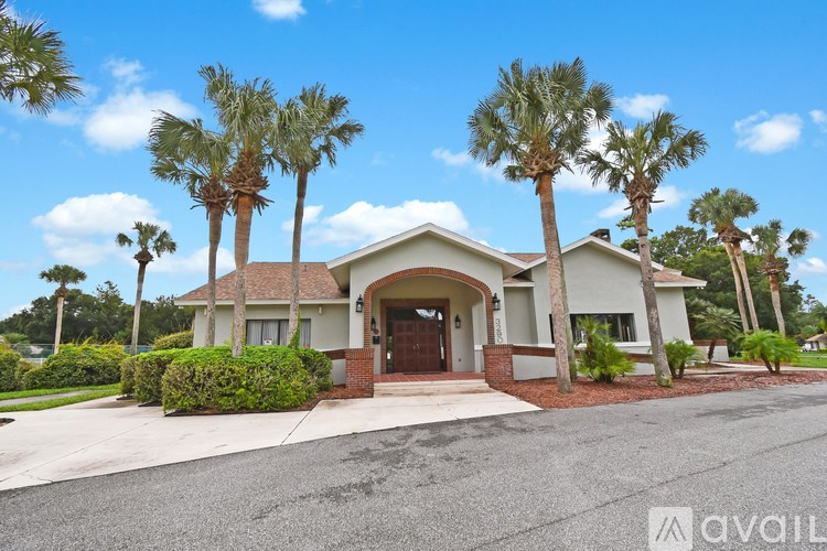 A house with a driveway and palm trees in front.