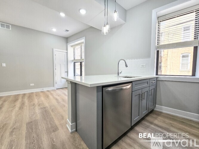A modern kitchen with a stainless steel dishwasher and wooden flooring.