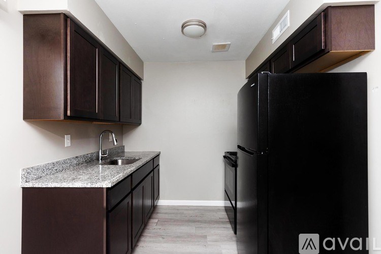 A kitchen with a black refrigerator and brown cabinets.