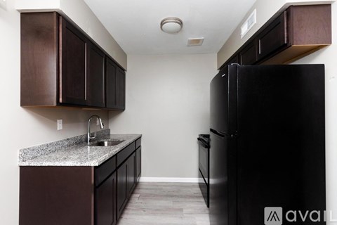 A kitchen with a black refrigerator and brown cabinets.