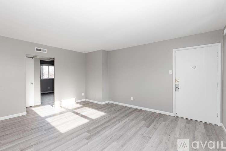 A spacious room with light wood flooring and white walls.