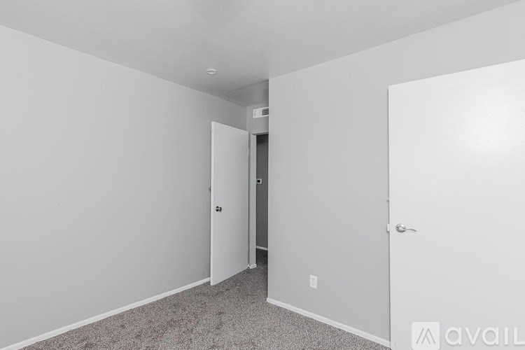 A room with a carpeted floor and two doors.
