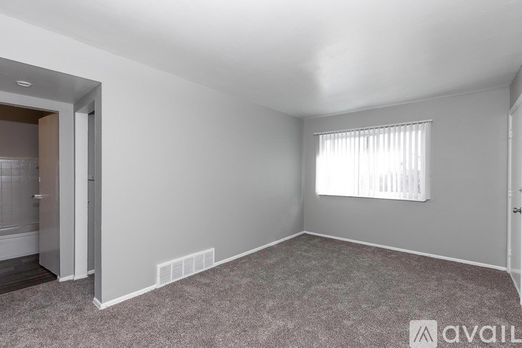 A room with a carpeted floor and a window with blinds.